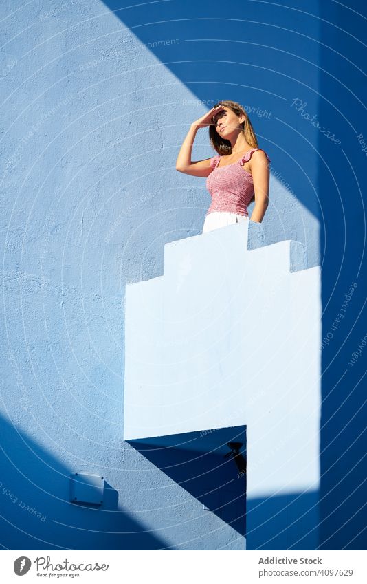 Woman standing on the top of a blue building woman long hair casual elegant construction stairs structure geometric architecture urban facade downtown center