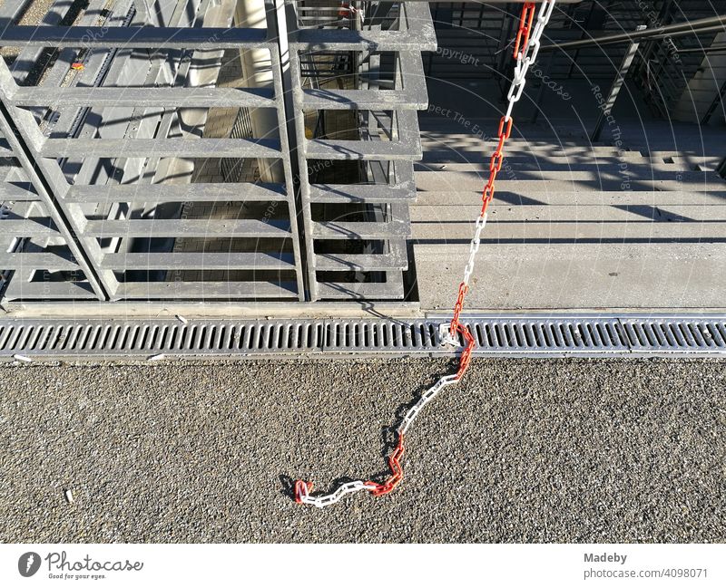 Torn off red and white barrier chain at a staircase at the fair in Cologne at the Rhine in sunshine in North Rhine-Westphalia, Germany Chain cordon