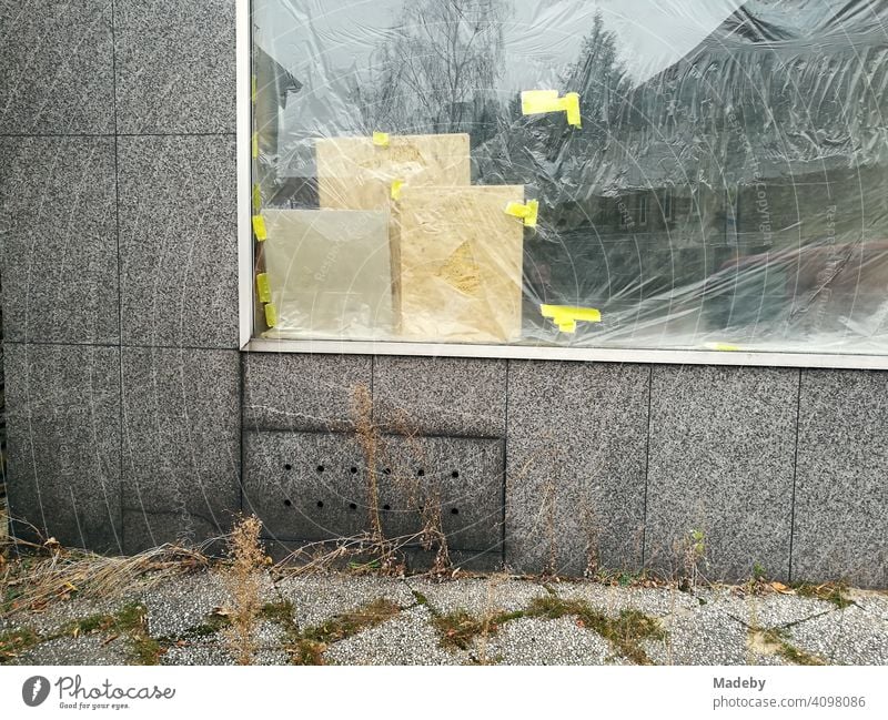 Shop window glued from the inside with foil in a grey facade with grey paving stones in Oerlinghausen near Bielefeld at the Hermannsweg in the Teutoburg Forest in East Westphalia-Lippe