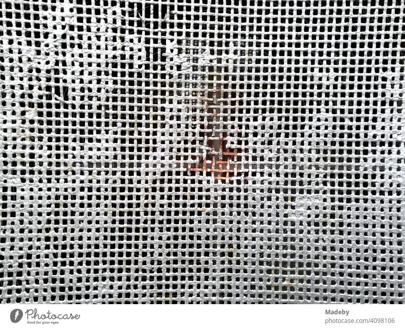White wire mesh with thick white paint remains and red rust in the middle in Oerlinghausen near Bielefeld on the Hermannsweg in the Teutoburg Forest in East Westphalia-Lippe