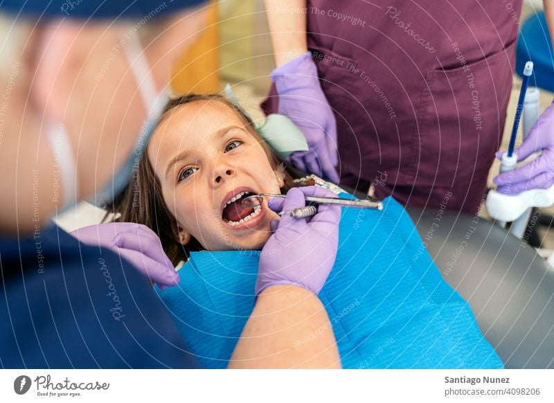 Young Girl During Checkup in Dentist examining front view kid girl young looking up dentist clinic dental clinic patient lying smile health care equipment