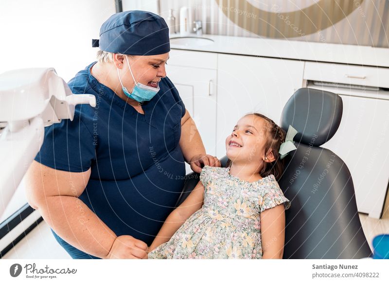 Dental Clinic Worker and Little Girl Smiling looking at each other woman worker patient little girl dental clinic smile smiling two people front view standing