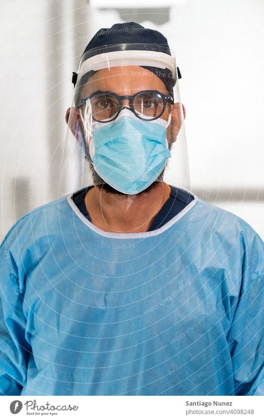 Dental Clinic Worker With Face Mask man looking at camera portrait face mask plastic face mask one person alone male glasses blue uniform dentist protection
