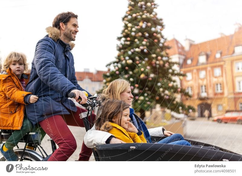 Young family riding in a cargo bicycle during Christmas cargo bike cycling transport tricycle healthy active biking modern sustainable transport ecological