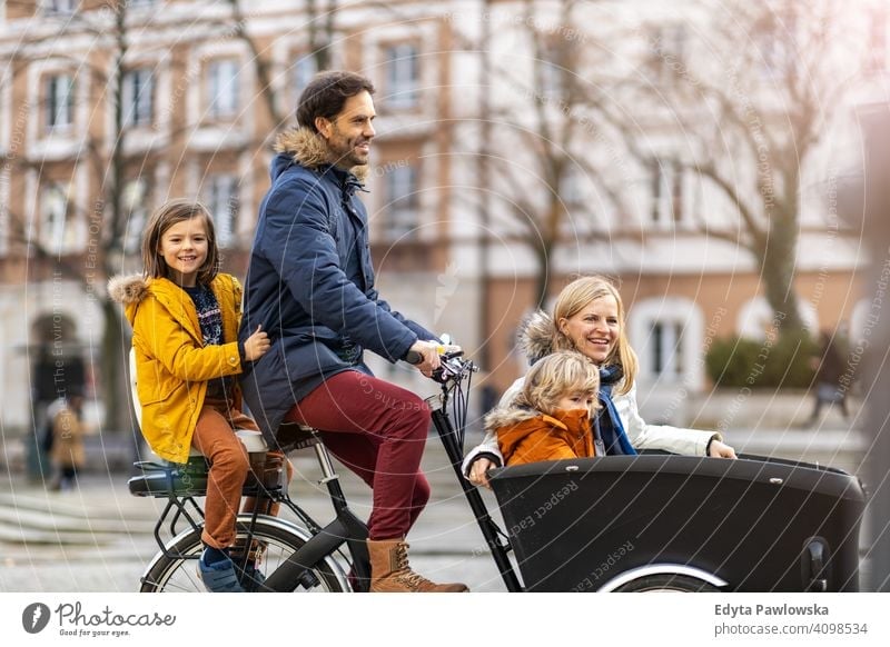 Young family riding in a cargo bike together cycling transport tricycle healthy active bicycle biking modern sustainable transport ecological travel young