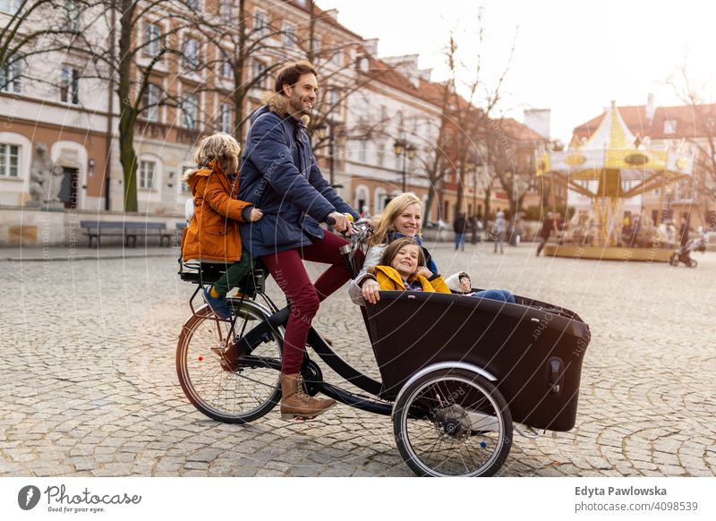 Young family riding in a cargo bike together cycling transport tricycle healthy active bicycle biking modern sustainable transport ecological travel young