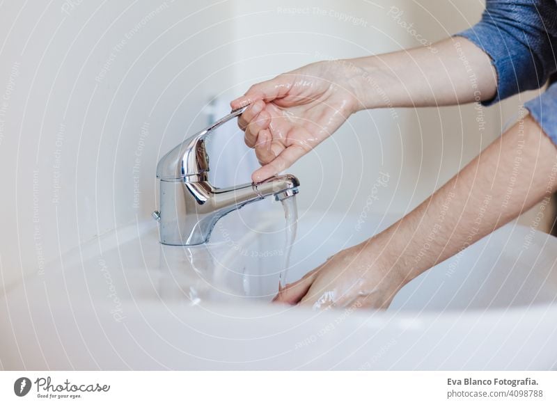 Closeup of caucasian woman washing hands in bathroom to prevent Covid-19 viral infection. Recommended washing with soap and running water during coronavirus pandemic