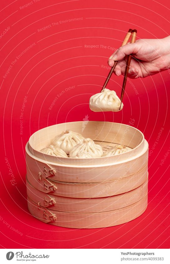 Woman hand taking chinese dumpling with wooden chopsticks arm asian asian food background bamboo bao baozi bun chinese food colorful cuisine culture cut out