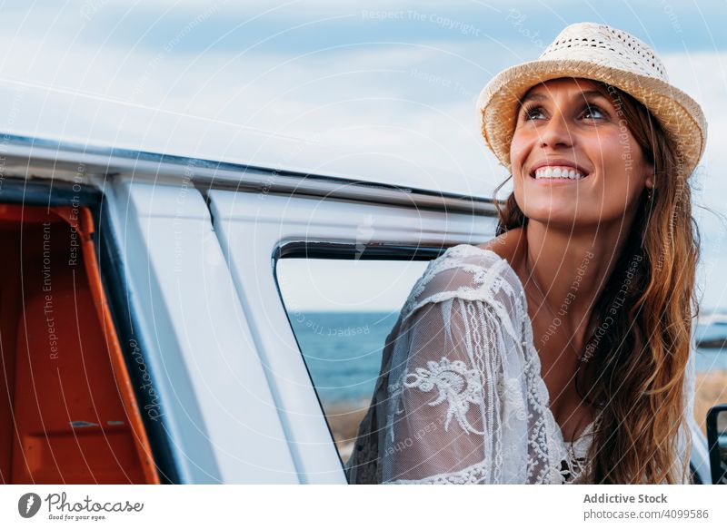 Smiling woman in hat in front seat of car opening door beach tourism travel freedom vehicle smiling transport joyful relaxation charming pleasure vacation ocean