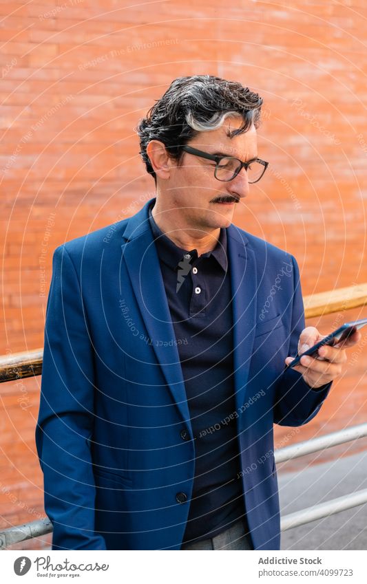 Senior businessman in blue jacket using smartphone browsing surfing mobile social media watching texting messaging adult aged senior communication internet