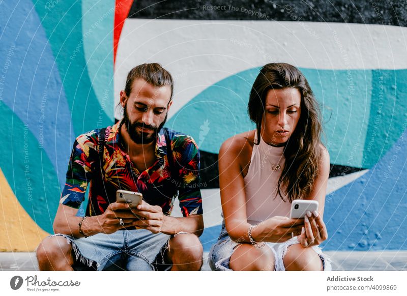 Couple sitting on floor and browsing smartphone friend city summer couple travel stroll together holiday street explore vacation urban ethnic memory moment aged