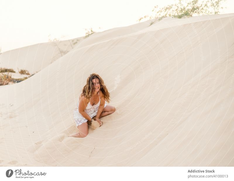 Woman sitting on sand in desert woman having fun throwing dune summer tropical vacation adult beautiful relax travel holiday playful recreation activity freedom