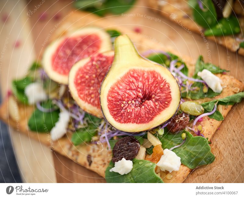 Ripe figs among herbs and flowers on cutting board rocket salad fresh fruit food refreshment meal rye bread exotic vegetable arugula slice ripe healthy aromatic