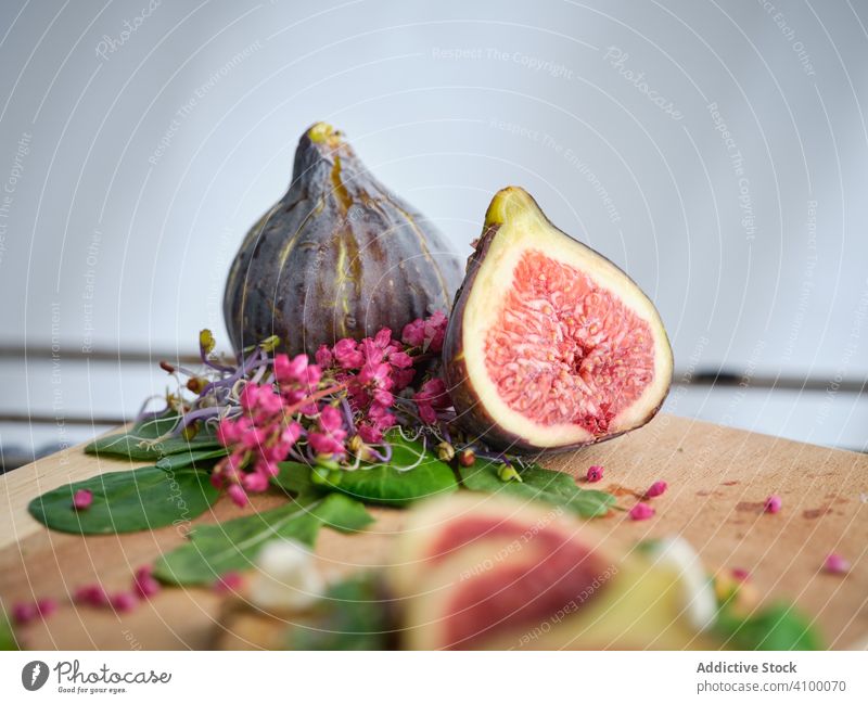 Ripe figs among herbs and flowers on cutting board rocket salad fresh fruit food refreshment meal rye bread exotic vegetable arugula slice ripe healthy aromatic