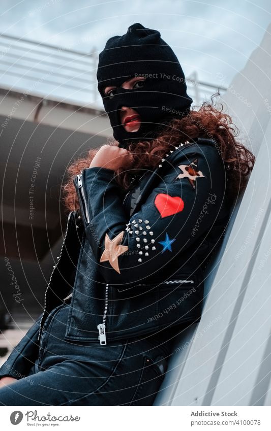 Woman in balaclava and black leather jacket woman mask rock style stripes urban street brunette fashion city outfit young female trendy underground clothes