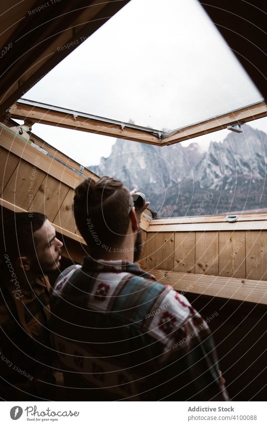 Men in casual wear enjoying views from ceiling window skylight modern wood inside room house wooden male tourism design mountain nature dolomites italy admire