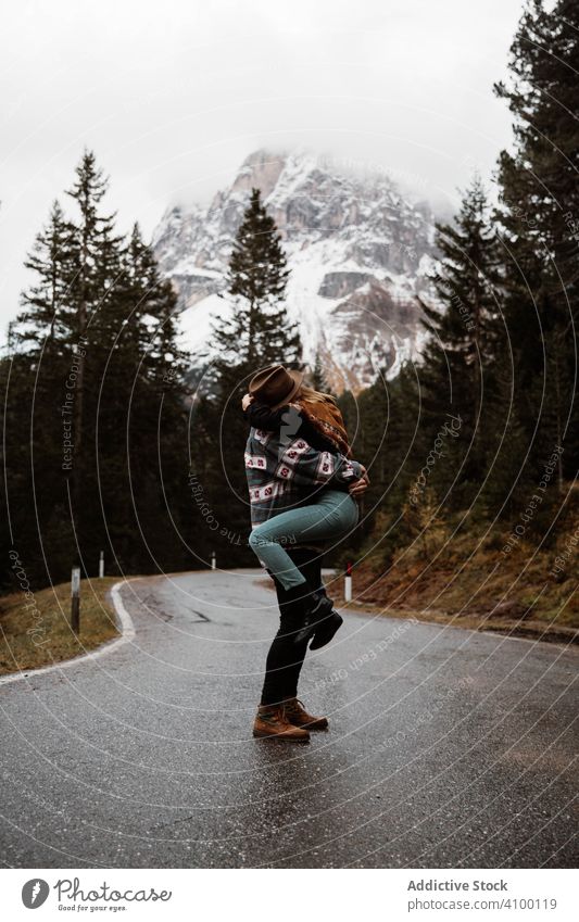 Casual resting couple standing in an embrace on route amid forest tourism hug pine mountains road highway travel nature vacation adventure young lifestyle