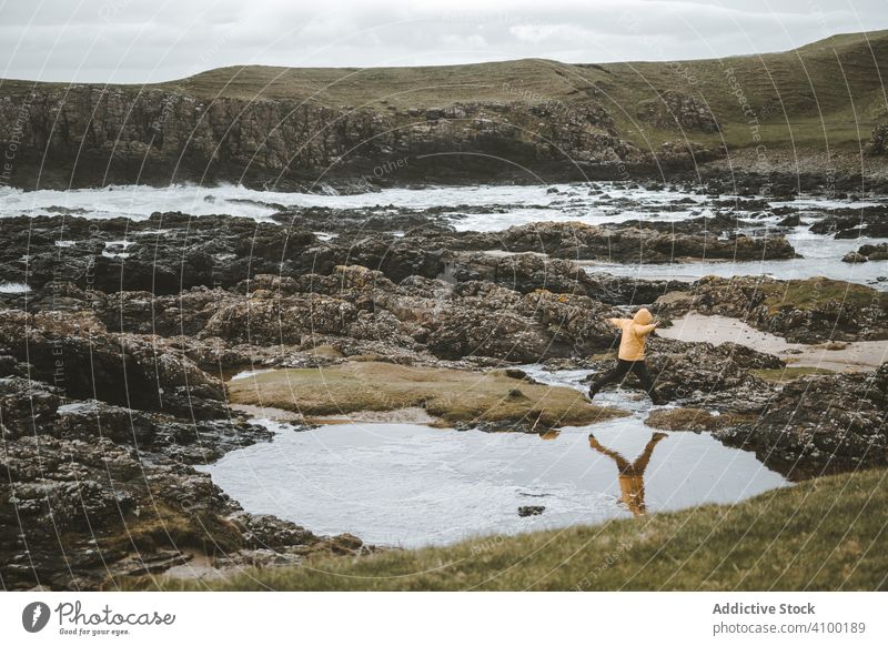 Man jumping over puddles of sea water on rocky shore coast man ocean cloudy northern ireland pool landscape mountain stone nature male scenic scenery walk