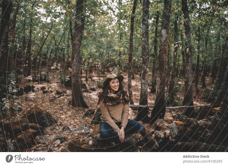 Young woman relaxing in forest ground sit tree nature adventure calm stylish female flora hat scarf tranquil serene peaceful lush foliage hiking green casual