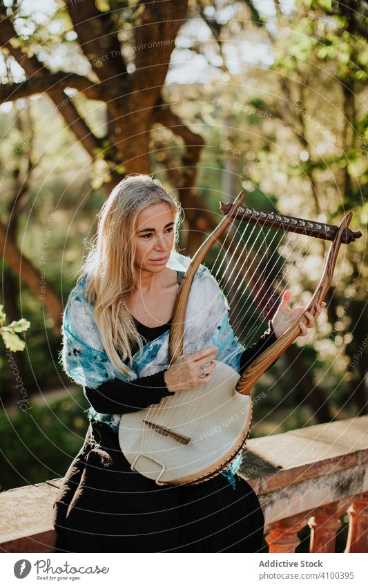 Sensual female musician playing lyre in garden romance woman ballade melody musical instrument talented summer sunny art inspiration muse dream classic