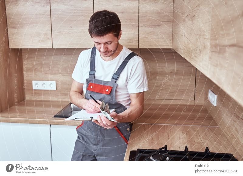 Plumber signs a contract for the services in the kitchen worker handyman repairman job profession technician maintenance male fix uniform overall plumber home