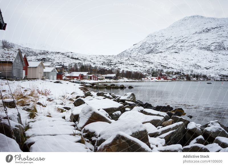 Tranquil lake against snowy hills in cold overcast weather fjord winter shore water norway ersfjordbotn highland calm beach solitude majestic environment fresh