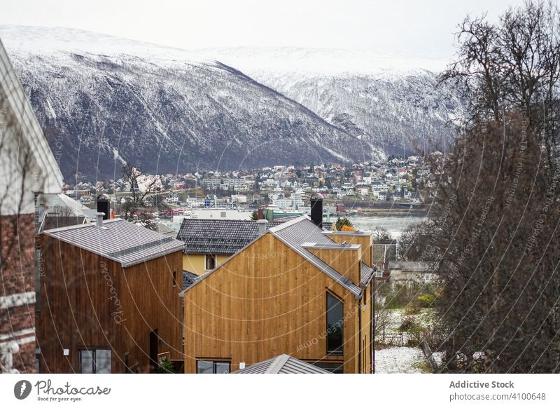 Wonderful scenery of winter city against snowy highland in cold overcast weather fjord house architecture foothill town scenic tourism urban valley nature