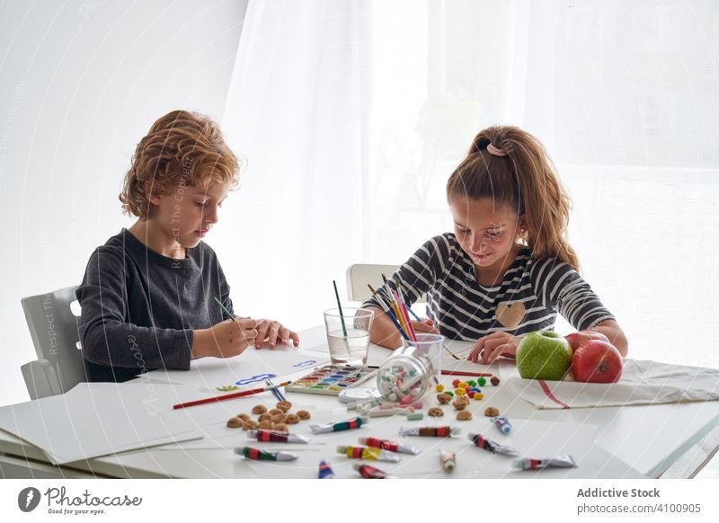 Focused kids painting at table children watercolor paintbrush focused friend home art creative education sit together girl boy pigment dye tool sibling sister