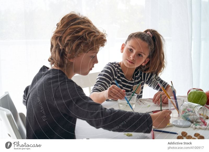 Focused kids painting at table children watercolor paintbrush focused friend home art creative education sit together girl boy pigment dye tool sibling sister