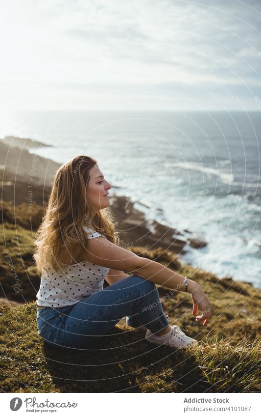 Pensive woman sitting on grass and looking at seascape dreamy coast pensive horizon freedom inspiration harmony seaside ocean cloudy sky style shore calm relax