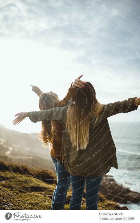 Happy female travelers enjoying freedom at seaside women breeze fresh flying hair sister stand harmony countryside together happy relax smile nature wind ocean