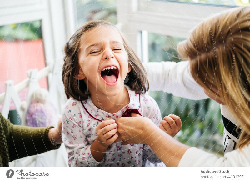 Cute little girl laughing from tickling tickle play fun mother happy family child childhood kid cute adorable dark hair joyful cheerful sit playful preschooler