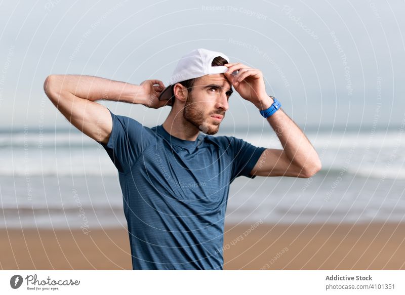 Confident male gymnast in active wear and cap on beach sportsman workout activewear seaside seashore lifestyle healthy exercise athlete training fit strength