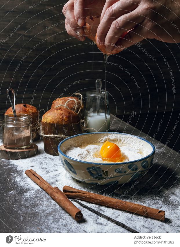 Cook breaking egg over bowl with flour panettone cake dough ingredient recipe bake bread hands prepare christmas dessert food knead making mixture bakery