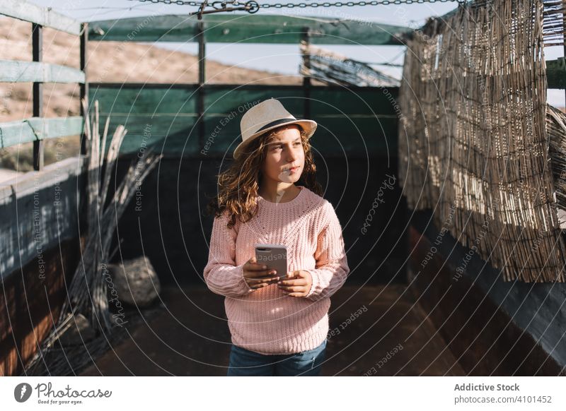 Focused girl using smartphone in countryside truck rest focused concentration car rose jumper casual straw hat attentive relax walk rusty mobile phone nature