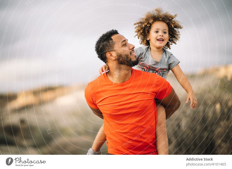 Black father holding child in arms toddler carry sportive smile play fun rest parent happy cheerful lifestyle modern nature man bonding love tender casual kid