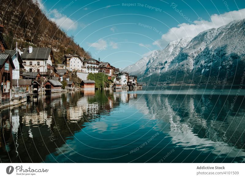 Mountain coast with houses along turquoise lake travel shore reflection mountain landscape nature cloudy crystal hallstatt scenic environment scenery vacation