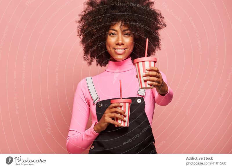 Happy black woman with disposable cup of drink standing against pink background happy straw african american laugh cheerful gesture ethnic female young casual