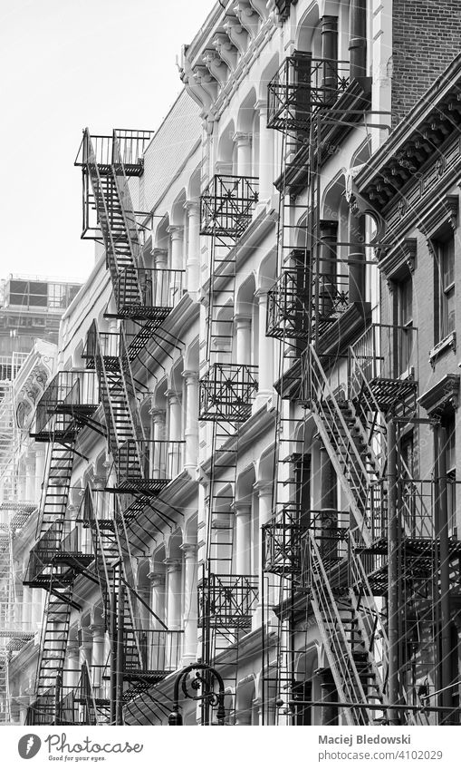 Row of old building with iron fire escapes, black and white picture of New York cityscape, USA. Manhattan townhouse architecture stairs apartment facade NYC