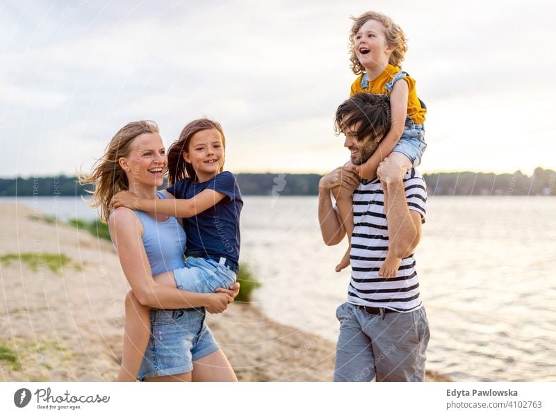 Young family having fun outdoors at the beach sea lake holidays vacation nature summer parents son boy kids children together togetherness love people happy