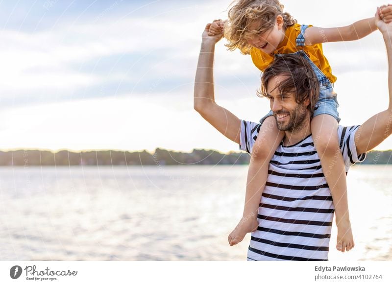Father with a child spending the day at the beach sea lake holidays vacation nature summer family parents son boy kids children together togetherness love
