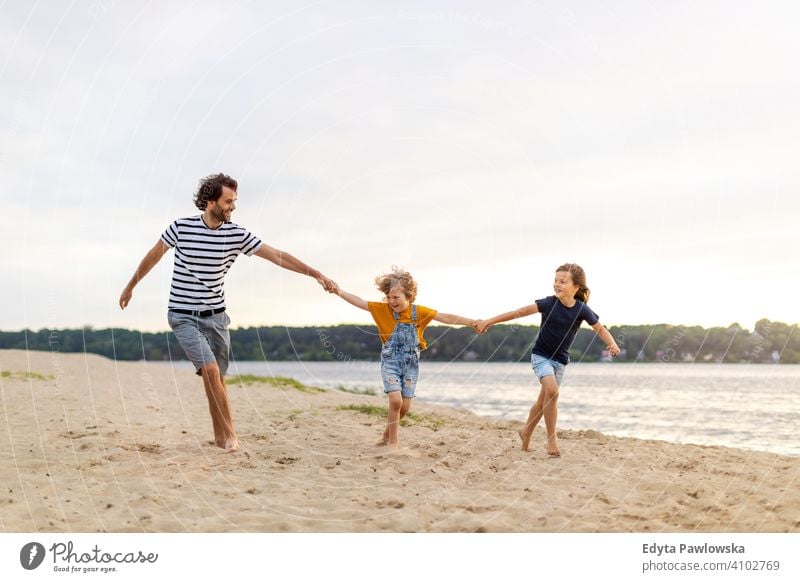Father with two children enjoying a day at the beach sea lake holidays vacation nature summer family parents son boy kids together togetherness love people