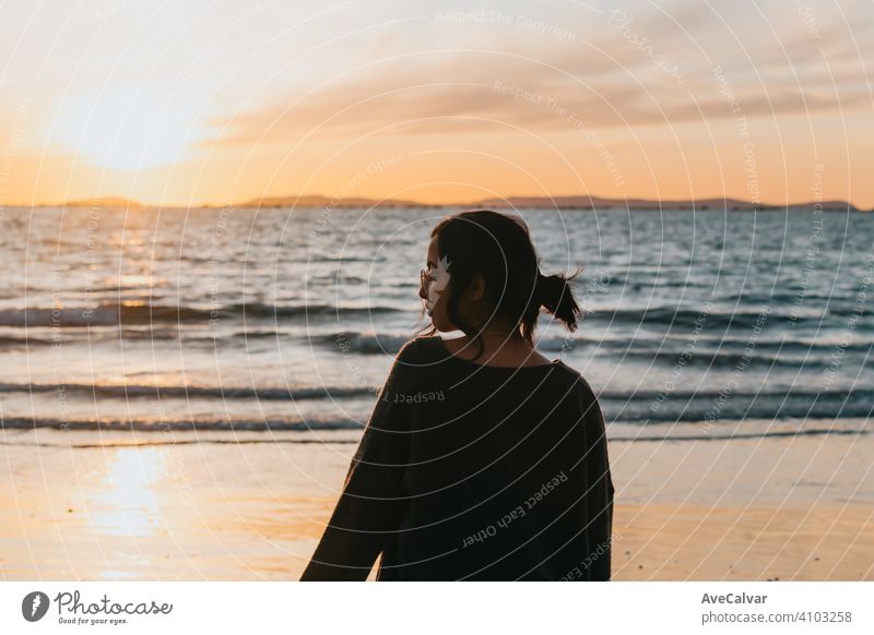 Woman in the beach looking a colorful sunset during a bright day with copy space carefree happiness person woman enjoyment freedom horizontal silhouette sunrise