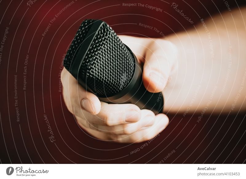 A hand grabbing a microphone over a red background record audio technology music professional sound radio recording studio apartment display dof dynamic