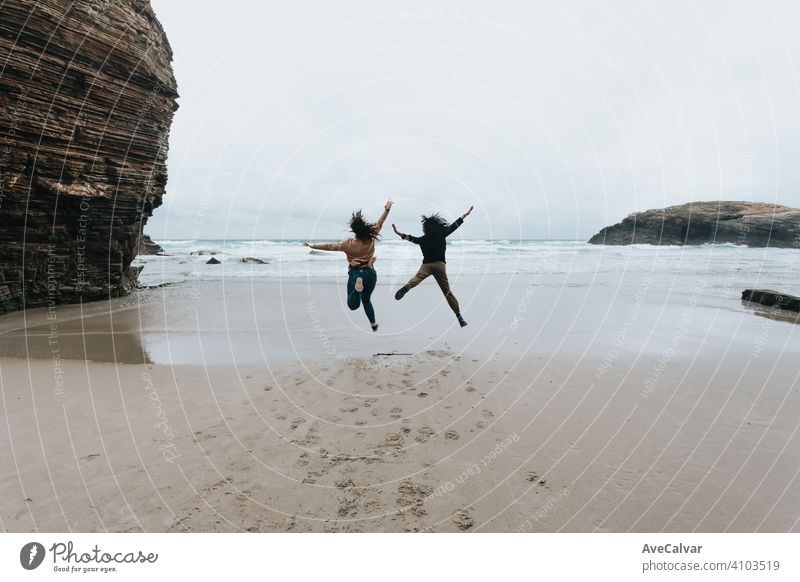 A couple of young women jumping in a wild beach with liberty during a sunny day with copy space happy woman together girlfriends two carefree excited friendship