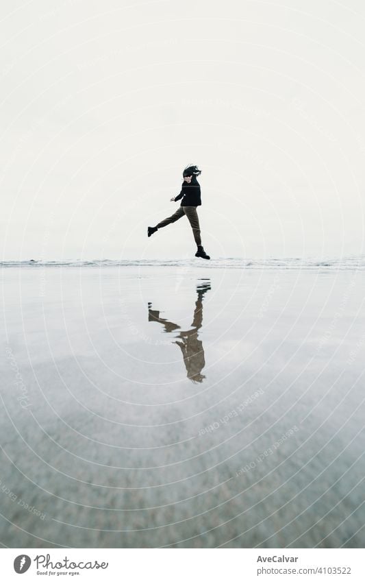 Young woman jumping jumping on the beach with a reflection over the water with copy space liberty concept person female ocean loneliness senior solitude lonely