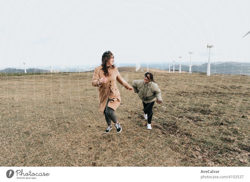 A couple of two women running and smiling liberty and happiness concept near wind mills during a cloudy day person lesbian copy-space woman dream heaven relax