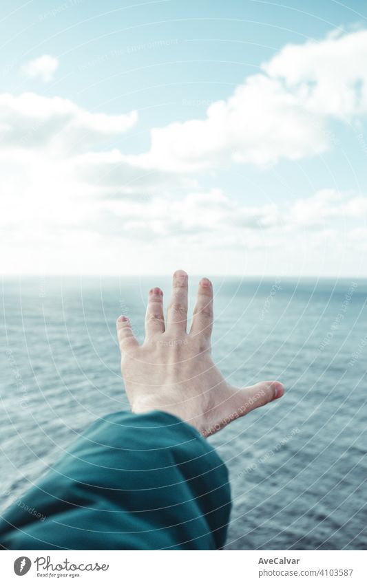 Hand of a man over a crystal clear horizon of the ocean with white clouds with copy space, inspiration and freedom concept paradise peace reflection wave indian