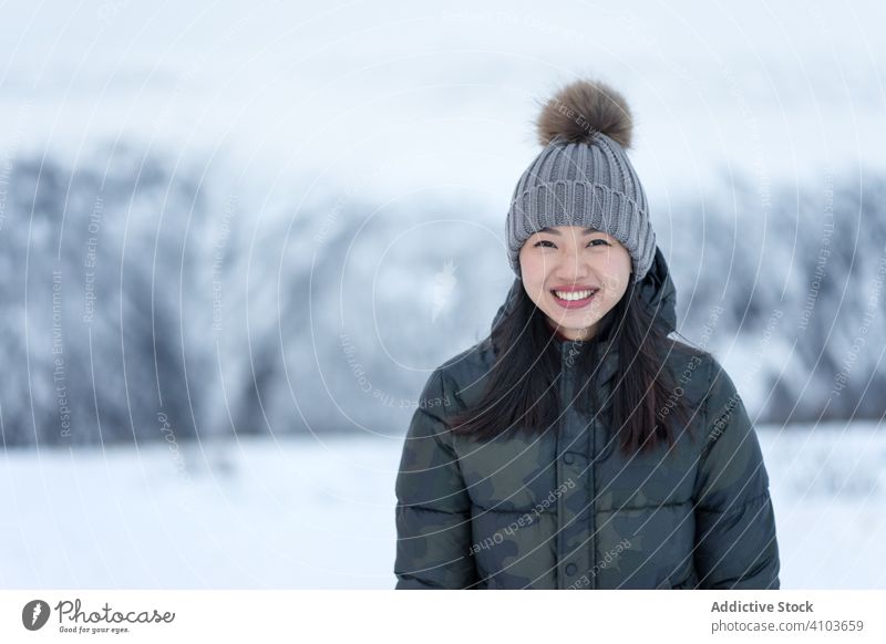Joyful woman in warm clothes against winter scenery eyes joy smile charm relax pleased happy beauty charismatic female nature cold snowy millennial face