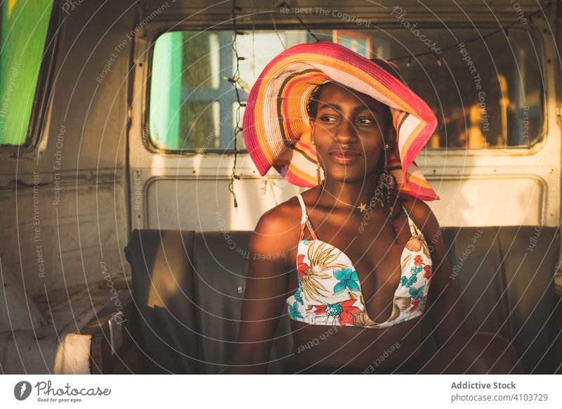 Happy African American female sitting behind wheel of car woman drive van vintage retro hat style happy smile enjoy fun outfit fashion african american colorful